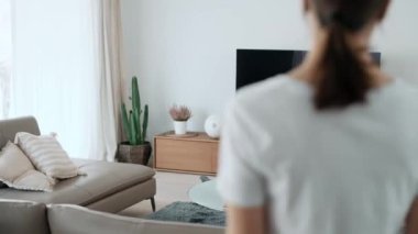 Elinde bez parçasıyla oturma odasını temizlemeye çalışan genç bir kadının videosu. 