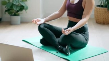 Spor yapan genç bir kadının yoga egzersizleri yaptığı video evde dizüstü bilgisayarla beden eğitimi derslerini takip ediyor..