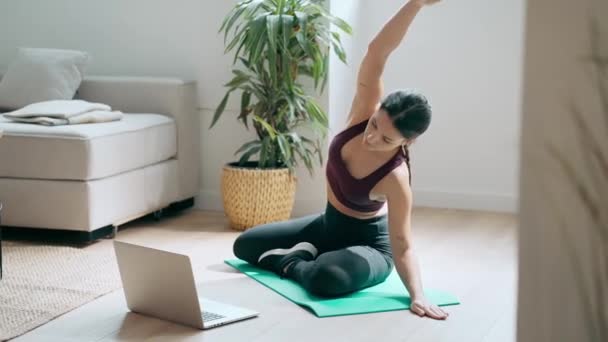 运动健美的年轻女子在家中通过笔记本电脑参加网上健身课程后进行瑜伽练习的视频 — 图库视频影像