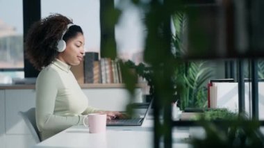 Ofiste kulaklıkla müzik dinlerken bilgisayarla çalışan zeki bir iş kadınının videosu.