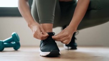 Spor ayakkabılarını evde bağlayan atletik kadının yakın çekim videosu..