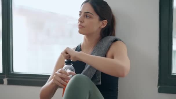 スポーティな若い女性のビデオ タンパク質シェイクを飲む ジムの後 自宅で床に座って — ストック動画