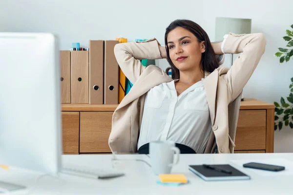 オフィスでコンピュータで作業しながら伸びる美しいエレガントなビジネス女性のショット — ストック写真