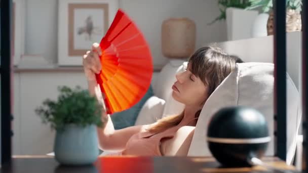 Video Hermosa Mujer Calentada Abanicándose Mientras Está Sentada Sofá Casa — Vídeos de Stock