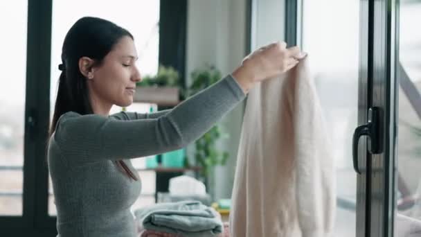 Видео Красивой Молодой Женщины Держащей Нюхающей Чистую Одежду Дома — стоковое видео