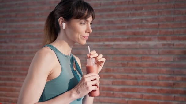 Video Hermosa Mujer Deportiva Goteando Batido Saludable Mientras Escucha Música — Vídeos de Stock