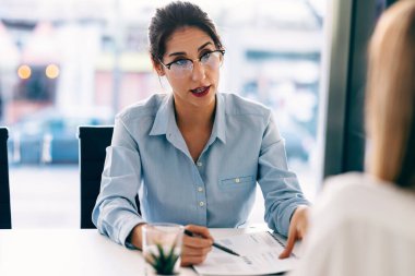 Modern bir girişimde birlikte çalışırken iki zarif iş kadınının konuşması.