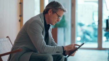 Yetişkin, yakışıklı girişimcinin dijital tabletle çalışırken birlikte çalıştığı bir koltukta oturduğu video.