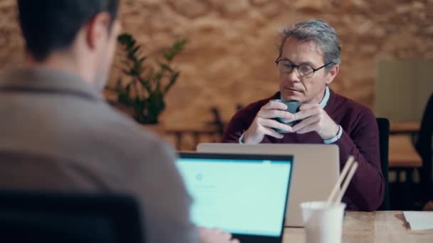 成熟したハンサムな起業家男性のビデオ コーヒーを飲みながら 同僚の場所でラップトップで作業 — ストック動画