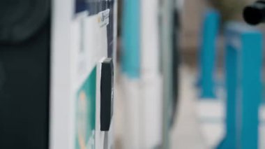 Akıllı telefondan ödeme yapan genç bir kadının elektrikli benzin istasyonundaki şarj elektro arabasının yakın çekim videosu.