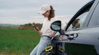 Doğayı görmek için arabayı durdururken akıllı telefon kullanan güzel bir genç kadının videosu.