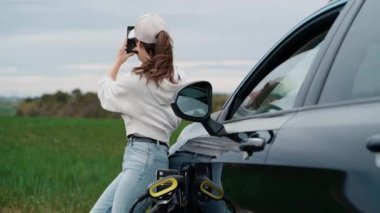 Doğayı görmek için arabayı durdururken akıllı telefonuyla fotoğraf çeken güzel bir genç kadının videosu.