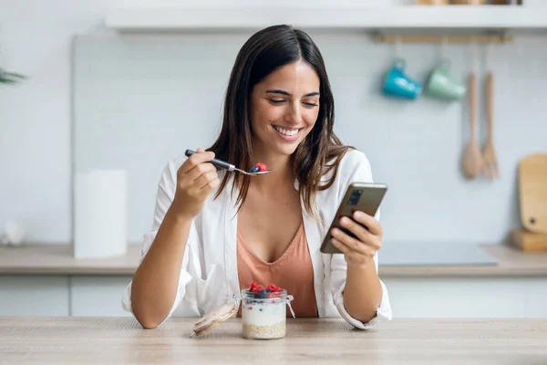 Colpo Bella Donna Mangiare Porridge Con Bacche Durante Utilizzo Smartphone — Foto Stock