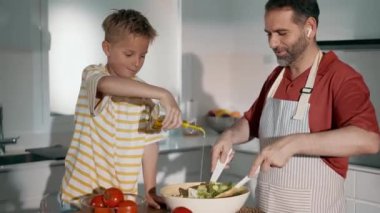 Yakışıklı babanın oğluyla evde sağlıklı salata pişirirken videosu.