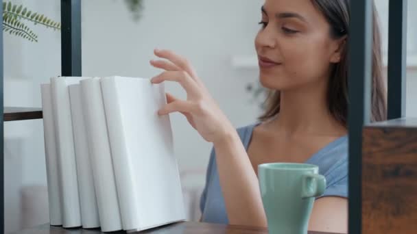 Video Hermosa Joven Bebiendo Una Taza Café Mientras Busca Libro — Vídeo de stock