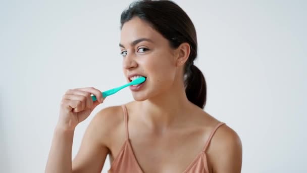 Dişlerini Fırçalarken Izole Edilmiş Beyaz Kameraya Bakan Genç Bir Kadının — Stok video