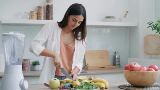 家庭でキッチンでデトックスジュースを準備するためにペプチーノを切る美女のビデオ — ストック動画