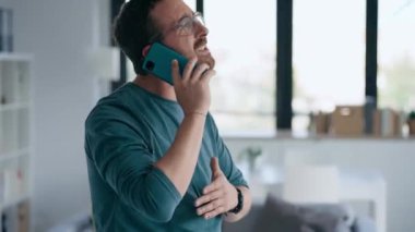 Evde cep telefonuyla konuşan sinirli bir adamın videosu.