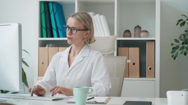 コンサルテーションでコンピュータで作業する成熟した女性医師のビデオ — ストック動画