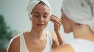 Evde aynaya bakarken cildine baktığı sırada makyajı kaldıran güzel bir genç kadının videosu..