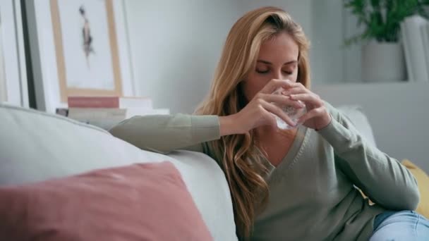 关于不健康的年轻女性头疼的视频 她把药丸放在家里沙发上的一杯水里 — 图库视频影像