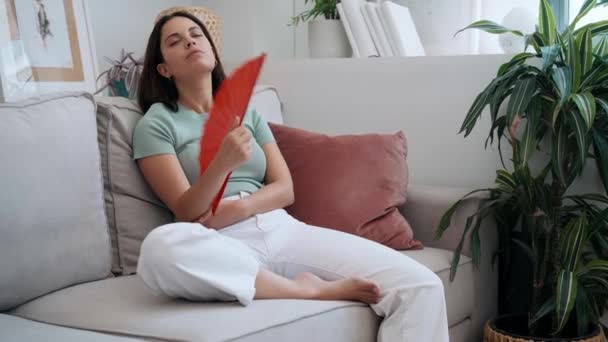 Video Hermosa Mujer Calentada Abanicándose Mientras Está Sentada Sofá Casa — Vídeo de stock