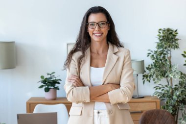 Ofiste kameraya bakarken gülümseyen genç ve güzel bir iş kadınının portresi.
