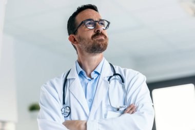 Ensesinde steteskop olan olgun bir erkek doktorun portresi tıbbi muayenede ileriye bakarken çalışıyor..