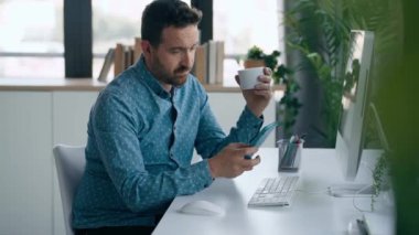 Ofiste cep telefonu kullanırken bilgisayarla çalışan olgun ve yakışıklı iş adamının videosu..