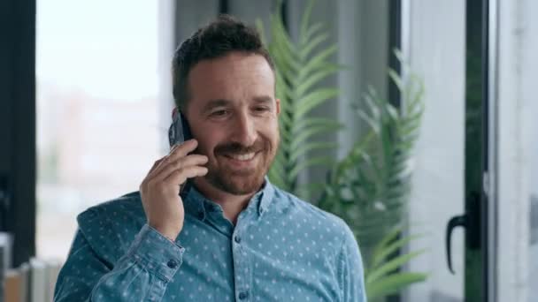 视频中的商人一边站在办公室的窗边一边一边用手机聊天 一边在一家现代初创公司工作 — 图库视频影像