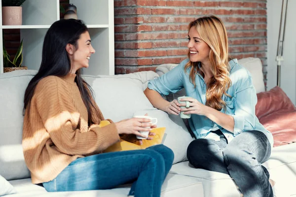 Tiro Dos Mujeres Jóvenes Sonrientes Hablando Mientras Beben Café Sentado — Foto de Stock