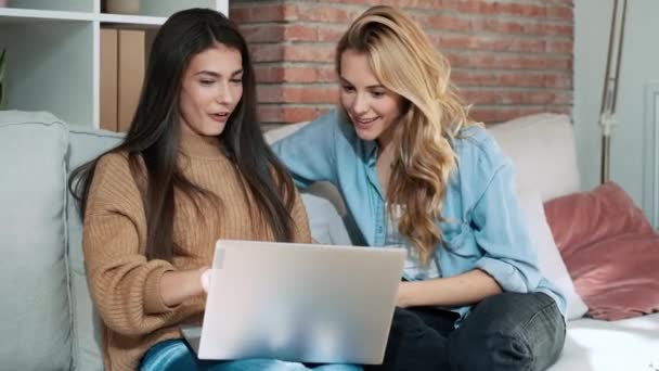 2人の幸せな女性の友人のビデオ 自宅のソファに座っているラップトップと一緒に旅行を検索することを祝う — ストック動画