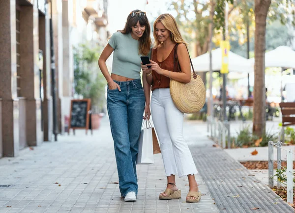 Girato Due Bellissimi Amici Che Parlano Usano Smartphone Mentre Camminano Fotografia Stock
