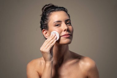 Güzel bir kadının makyajını temizlerken, arka plandaki kameraya bakarken çekilmesi.