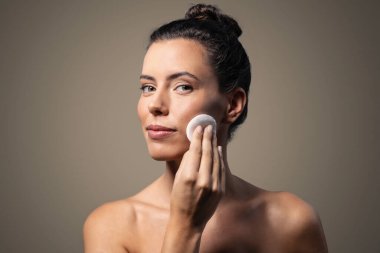 Güzel bir kadının makyajını temizlerken, arka plandaki kameraya bakarken çekilmesi.