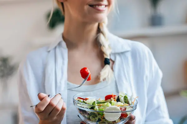 Nærbillede Smilende Kvinde Der Spiser Sund Salat Mens Sidder Køkkenet Royaltyfrie stock-fotos