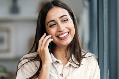 Güzel bir kadının evinin penceresinin yanında beklerken cep telefonuyla konuşması.