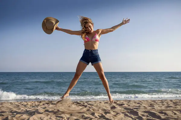 拍美丽的年轻女子享受自由的同时跳到海滩 — 图库照片