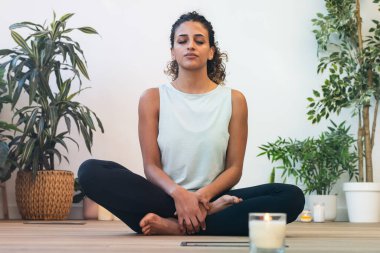 Evde nilüfer pozisyonunda otururken yoga egzersizleri yapan genç bir kadın..
