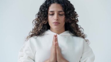 Beyaz eşofman giymiş, stüdyoda yoga pozu veren barışçıl bir kadının videosu.
