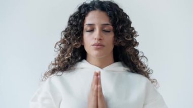 Beyaz eşofman giymiş, stüdyoda yoga pozu veren barışçıl bir kadının videosu.
