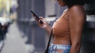 Gülümseyen bir kadının alışveriş çantalarını taşırken akıllı telefon kullandığı video.