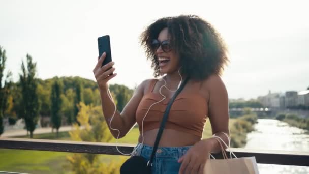 在街上与智能手机进行视频交谈的快乐年轻女性的视频 — 图库视频影像