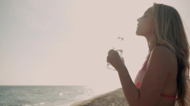 Kumsalda su içerken özgürlüğün tadını çıkaran güzel genç bir kadının videosu.