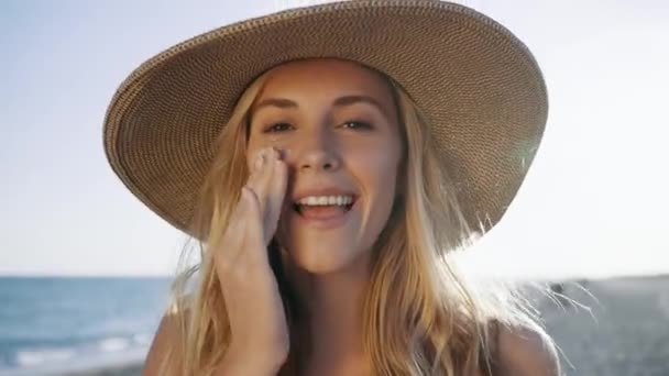 在海滩上看相机时 漂亮的微笑女人在脸上涂防晒霜的视频 — 图库视频影像