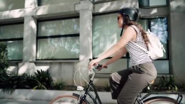 Şehrin içinde elektrikli scooter kullanan kendinden emin, neşeli bir kadının videosu.