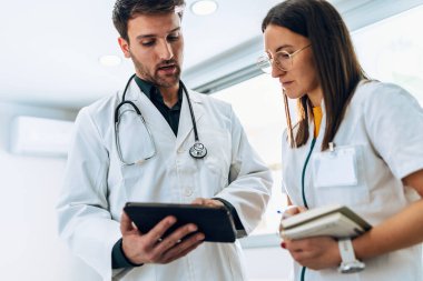 Tıbbi konsültasyonda tıbbi bilgiler hakkında konuşan akıllı kadın ve erkek doktorların iğnesi.