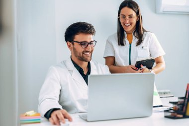 Kendine güvenen kadın ve erkek doktorların tıbbi danışmanlık sırasında dizüstü bilgisayarla konuşmaları ve oynaşmaları..
