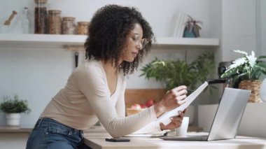 Evde dizüstü bilgisayarla çalışan neşeli ve çekici bir kadının videosu..