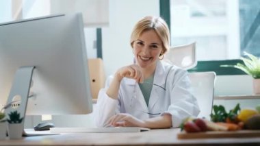 Beslenme danışmanlığında kameraya bakarken bilgisayarla çalışan güzel ve zeki bir beslenme uzmanı kadının videosu.